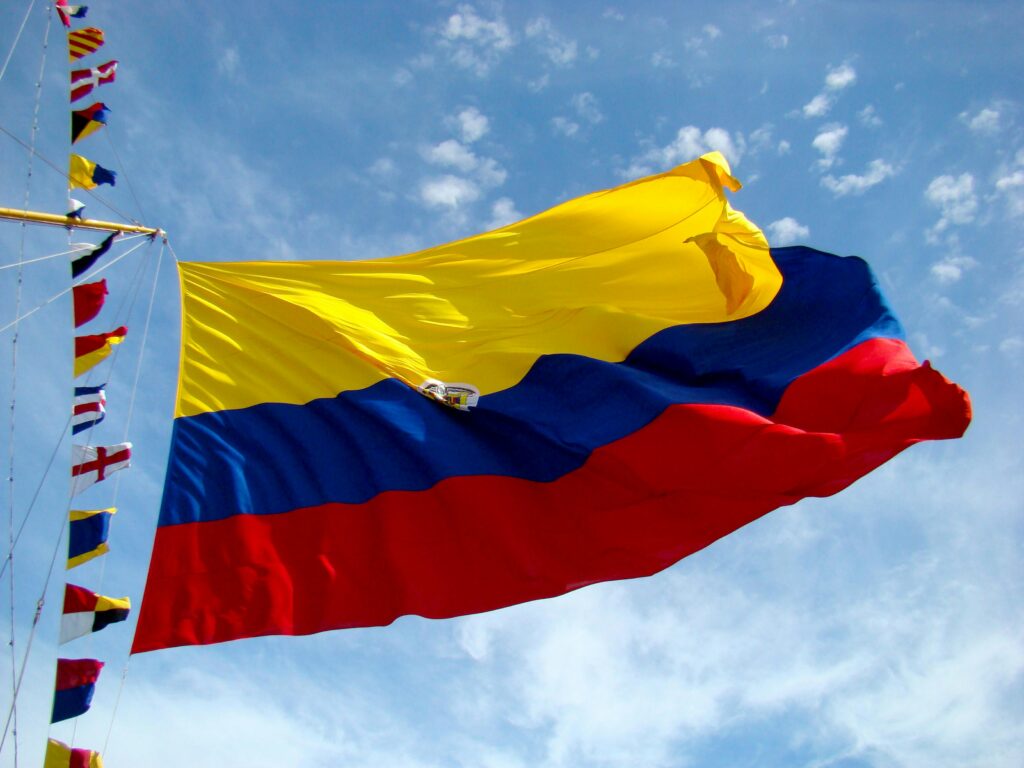 Vibrant Colombian flag waving against a bright blue sky with additional colorful maritime flags.